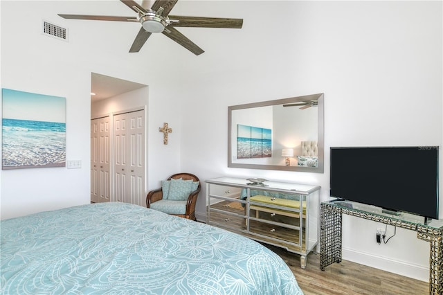 bedroom featuring ceiling fan, visible vents, two closets, and wood finished floors