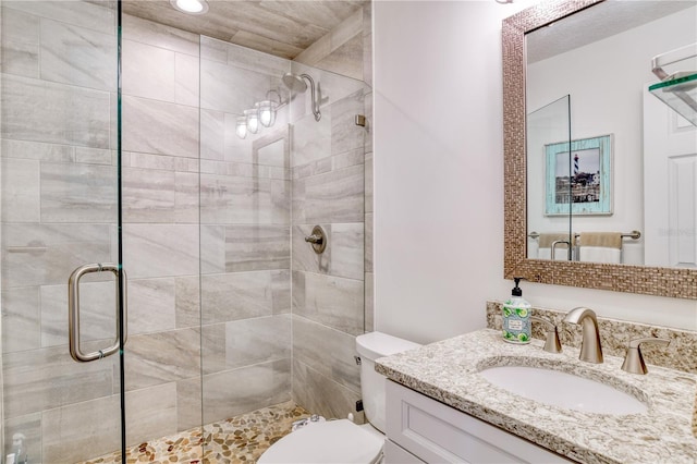 full bathroom featuring a shower stall, toilet, and vanity