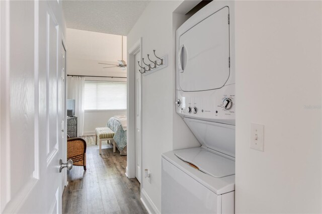 laundry area with hardwood / wood-style floors, ceiling fan, stacked washer and dryer, and a textured ceiling