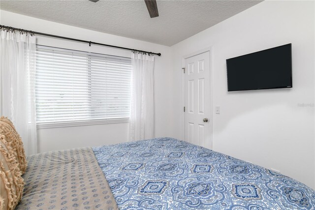 bedroom featuring a textured ceiling, ceiling fan, and multiple windows