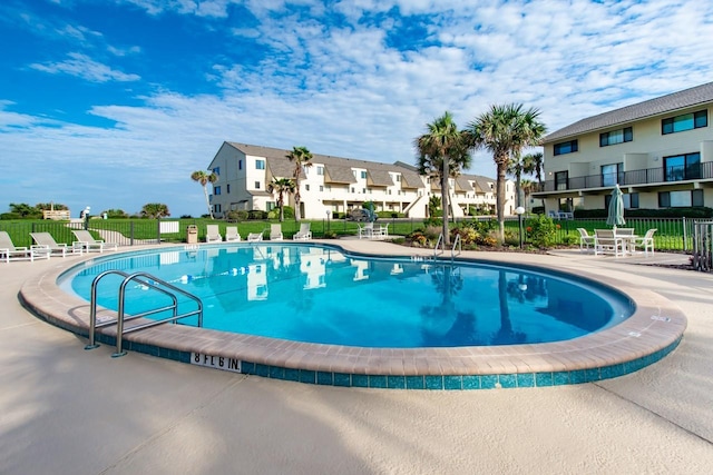 community pool featuring a patio area, a residential view, and fence