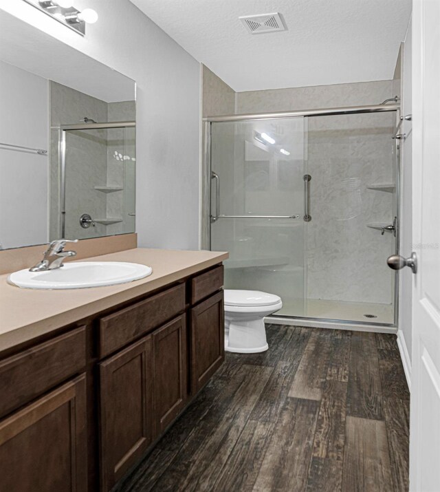 bathroom with wood finished floors, a stall shower, toilet, and vanity