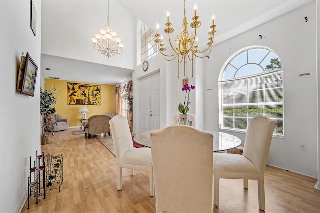 dining space featuring a notable chandelier, light wood-type flooring, and a high ceiling