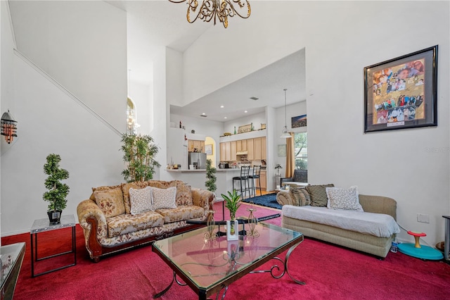 living room with a notable chandelier, a towering ceiling, and carpet flooring