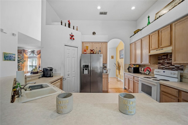 kitchen with light hardwood / wood-style floors, stainless steel fridge with ice dispenser, sink, electric stove, and decorative backsplash