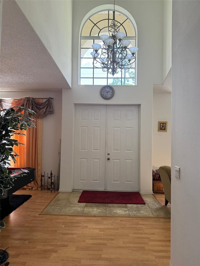 entrance foyer featuring light wood-type flooring, a high ceiling, and an inviting chandelier