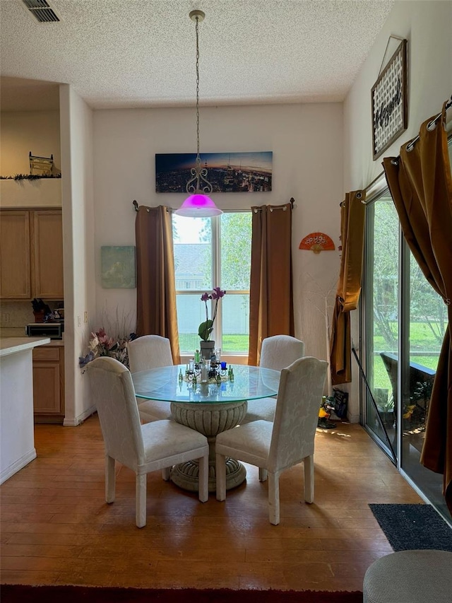 dining space with a textured ceiling, light hardwood / wood-style flooring, and a wealth of natural light