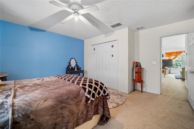 carpeted bedroom with ceiling fan, a textured ceiling, and a closet