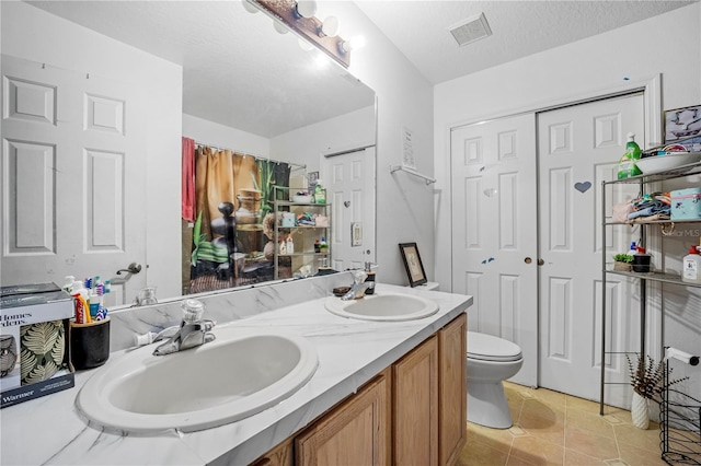 bathroom featuring tile patterned floors, a textured ceiling, vanity, and toilet