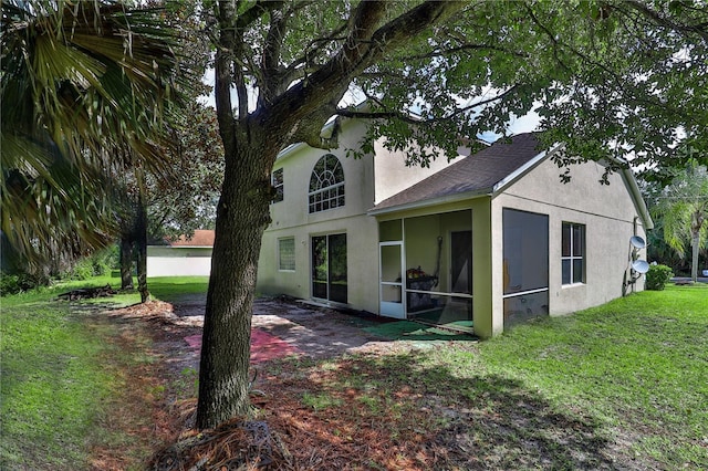 back of property featuring a lawn, a patio, and a sunroom