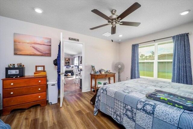 bedroom with a textured ceiling, hardwood / wood-style flooring, and ceiling fan