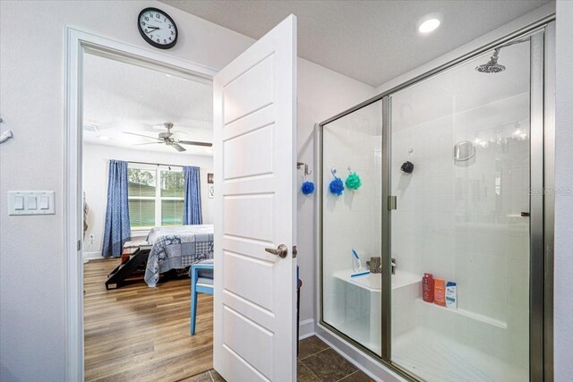 bathroom with a textured ceiling, a shower with shower door, ceiling fan, and hardwood / wood-style floors