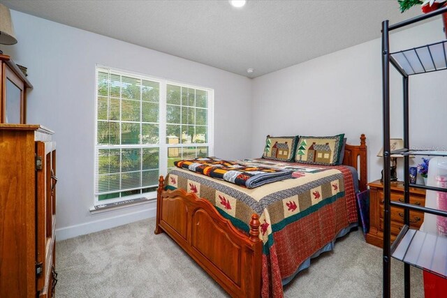 carpeted bedroom featuring a textured ceiling and multiple windows