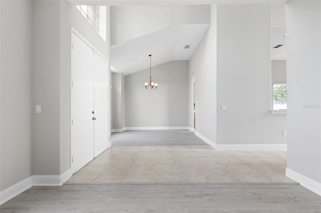 hall featuring high vaulted ceiling and an inviting chandelier