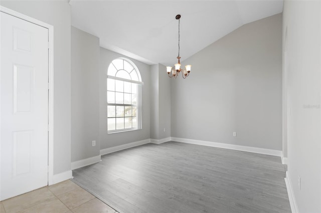 empty room featuring light hardwood / wood-style floors, an inviting chandelier, and vaulted ceiling