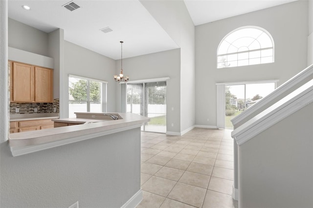 kitchen featuring light tile patterned floors, decorative light fixtures, a chandelier, sink, and decorative backsplash