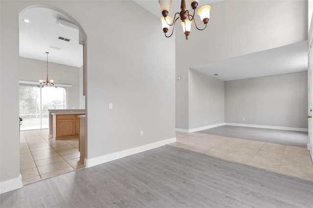 tiled empty room with high vaulted ceiling and an inviting chandelier