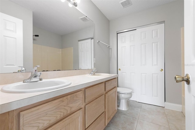 bathroom featuring tile patterned flooring, toilet, a textured ceiling, and vanity