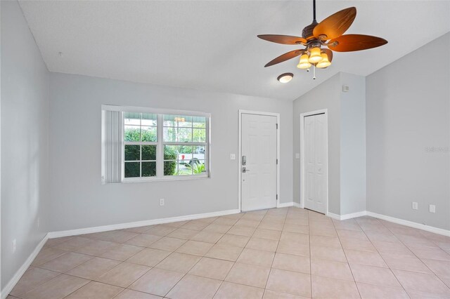 tiled spare room featuring ceiling fan and vaulted ceiling