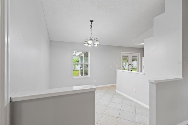 empty room with a textured ceiling, an inviting chandelier, light tile patterned floors, and sink