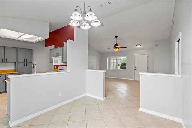 kitchen featuring ceiling fan with notable chandelier, white appliances, light tile patterned floors, vaulted ceiling, and gray cabinetry