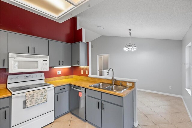 kitchen featuring white appliances, kitchen peninsula, sink, hanging light fixtures, and vaulted ceiling