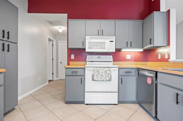 kitchen featuring gray cabinets, white appliances, and light tile patterned floors