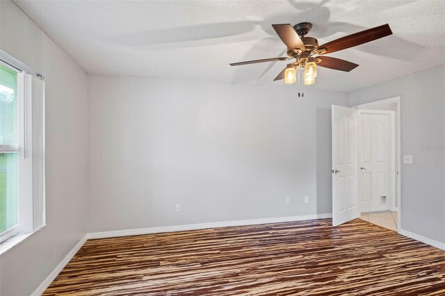 empty room featuring ceiling fan, dark hardwood / wood-style floors, and a textured ceiling