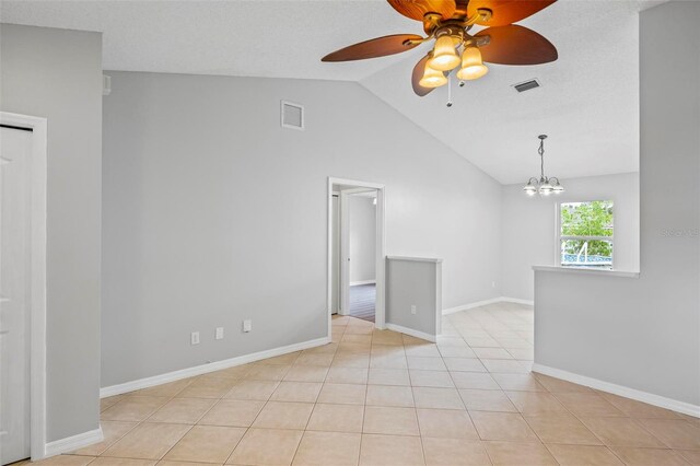 tiled empty room featuring ceiling fan with notable chandelier, lofted ceiling, and a textured ceiling