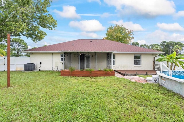 back of property with a lawn, a sunroom, and central AC