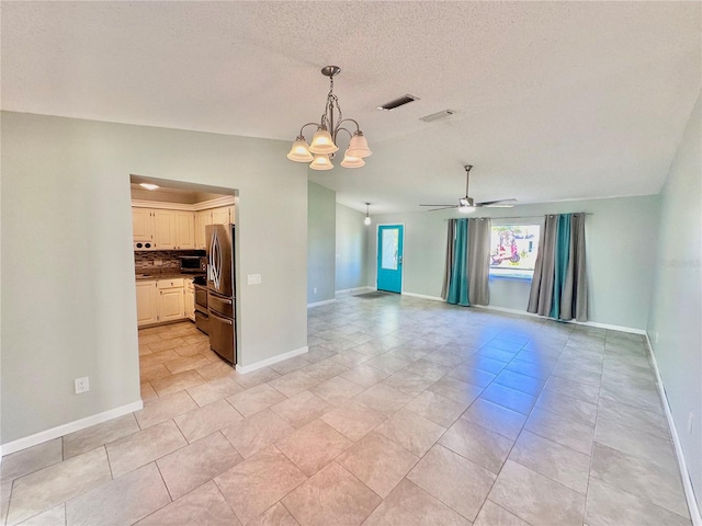 tiled empty room with a textured ceiling and ceiling fan with notable chandelier