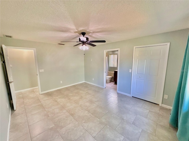 unfurnished bedroom featuring ceiling fan, ensuite bathroom, and a textured ceiling