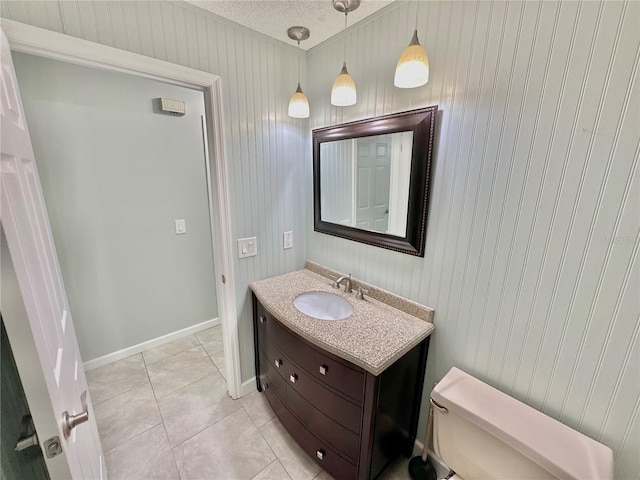 bathroom with a textured ceiling, wooden walls, tile patterned floors, vanity, and toilet