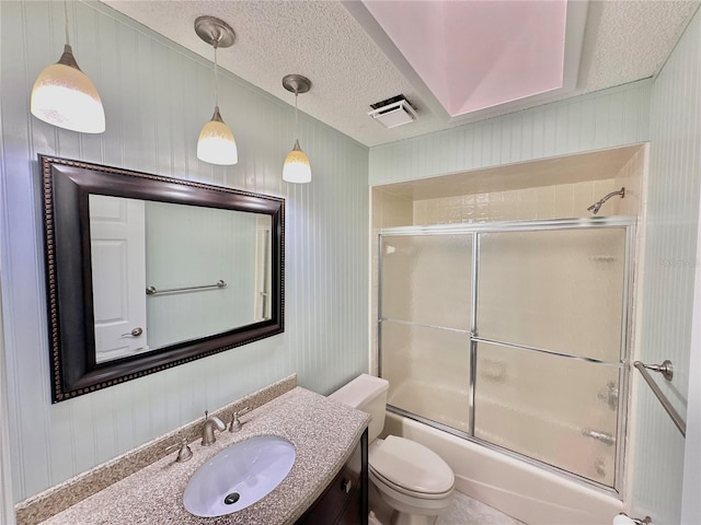 full bathroom with a textured ceiling, bath / shower combo with glass door, toilet, and vanity