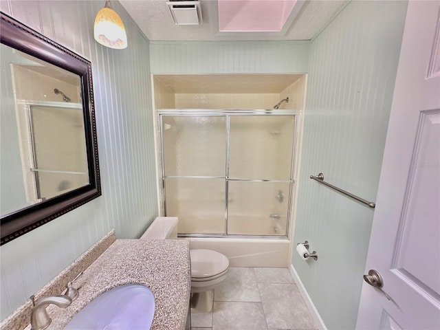 full bathroom with bath / shower combo with glass door, toilet, vanity, and tile patterned floors