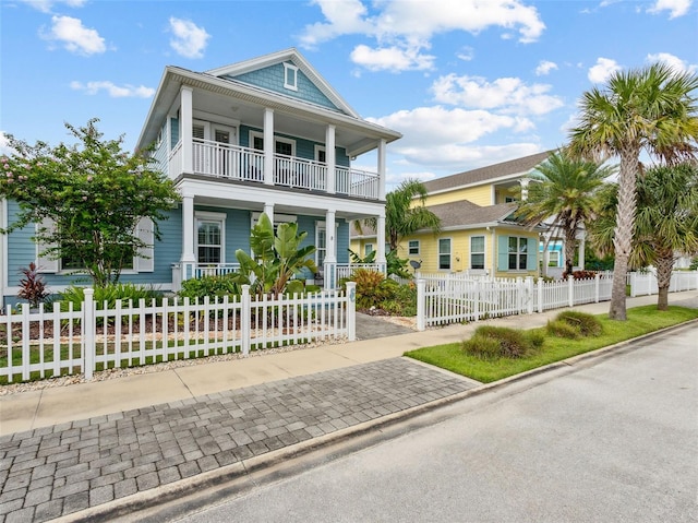 view of front of home featuring a fenced front yard, covered porch, and a balcony