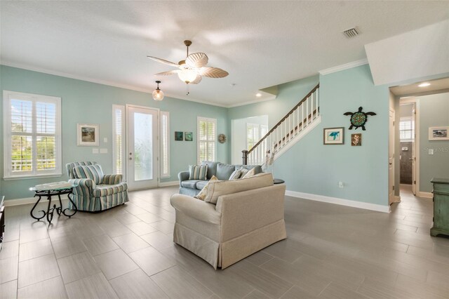 living room with ceiling fan, crown molding, and a healthy amount of sunlight