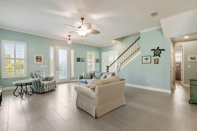 living area featuring visible vents, crown molding, baseboards, ceiling fan, and stairs