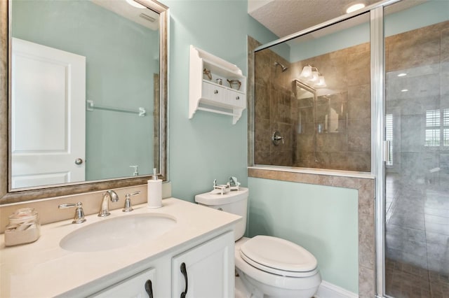 bathroom with toilet, vanity, a shower with door, and a textured ceiling