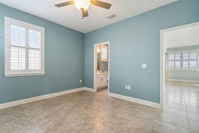 spare room with a textured ceiling, ceiling fan, and light tile patterned flooring