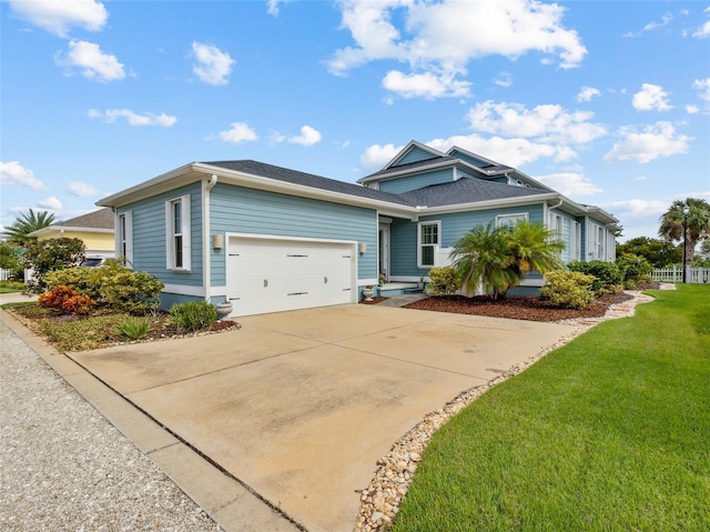 view of front of house featuring a garage, concrete driveway, a front lawn, and fence