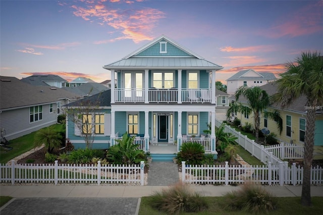 view of front facade with a fenced front yard, a balcony, covered porch, and a gate