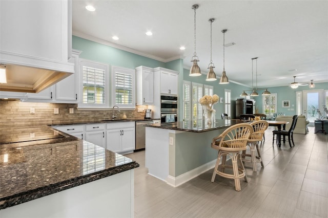 kitchen with white cabinets, appliances with stainless steel finishes, a center island, sink, and ceiling fan