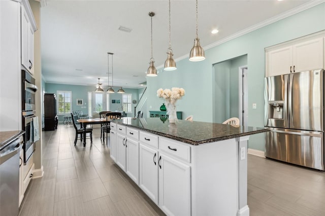 kitchen with stainless steel appliances, dark stone countertops, white cabinets, and a kitchen island