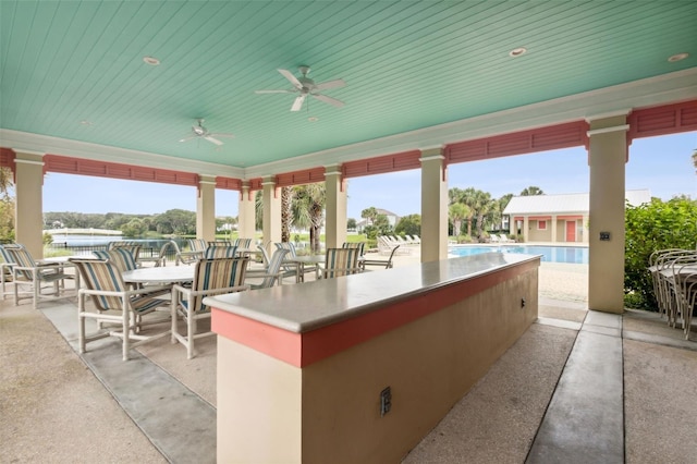 view of patio / terrace featuring ceiling fan, a bar, and a community pool