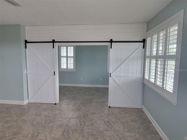 empty room with a textured ceiling and a barn door