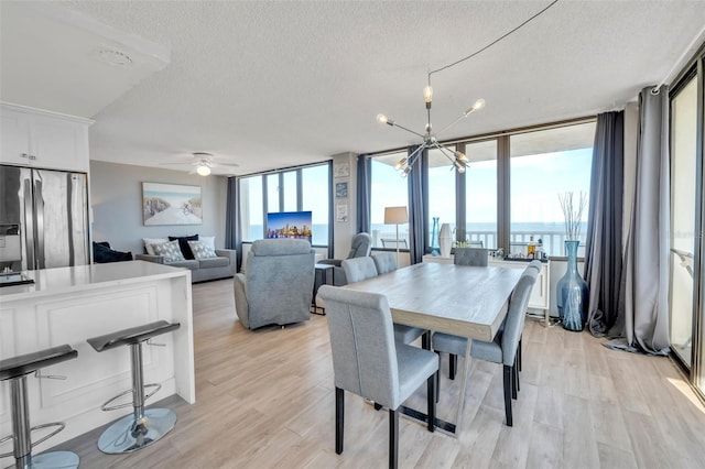 dining space featuring light hardwood / wood-style flooring, a wall of windows, and a wealth of natural light