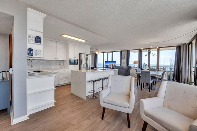 kitchen with a kitchen island, white cabinetry, appliances with stainless steel finishes, and a healthy amount of sunlight