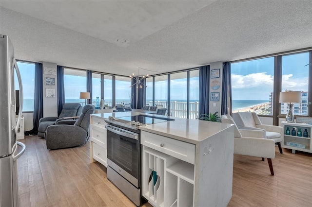 kitchen with a wall of windows, stainless steel appliances, a water view, and white cabinetry