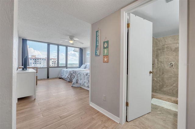 bedroom with light hardwood / wood-style flooring, floor to ceiling windows, ceiling fan, and a textured ceiling